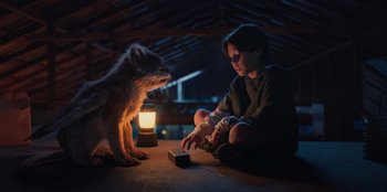 Movie still from “Chupa” (2023), directed by Jonás Cuarón – A person sitting on the ground next to an animal; Medium shot, High angle