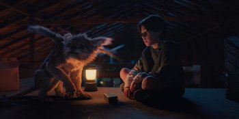 Movie still from “Chupa” (2023), directed by Jonás Cuarón – A person sitting on the ground next to a dog; Medium shot, High angle