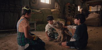 Movie still from “Chupa” (2023), directed by Jonás Cuarón – A group of children petting a dog in a room; Medium shot, High angle