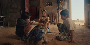 Movie still from “Chupa” (2023), directed by Jonás Cuarón – A group of children sitting on the ground with a cat; Medium shot, High angle