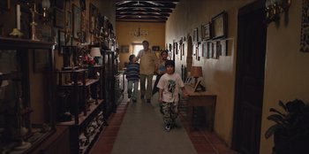 Movie still from “Chupa” (2023), directed by Jonás Cuarón – A man and two boys walking down a long hallway; Wide shot, Over the shoulder angle