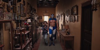 Movie still from “Chupa” (2023), directed by Jonás Cuarón – A man in a wrestling outfit walking down a hallway; Wide shot, Low angle