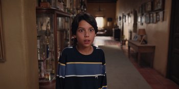 Movie still from “Chupa” (2023), directed by Jonás Cuarón – A young boy standing in a room filled with trophies; Close Up shot, High angle
