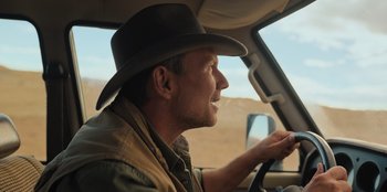 Movie still from “Chupa” (2023), directed by Jonás Cuarón – A man wearing a cowboy hat driving a car; Close Up shot, Over the shoulder angle