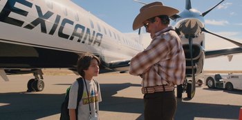 Movie still from “Chupa” (2023), directed by Jonás Cuarón – A man and a boy standing in front of an airplane; Medium shot, Over the shoulder angle