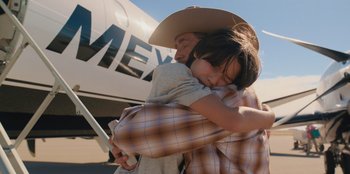 Movie still from “Chupa” (2023), directed by Jonás Cuarón – A man and a child hug in front of an airplane; Medium shot, Over the shoulder angle