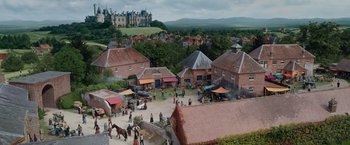 Movie still from “Cinderella” (2021), directed by Kay Cannon – A group of people riding horses in front of a building; Extreme Wide shot, High angle