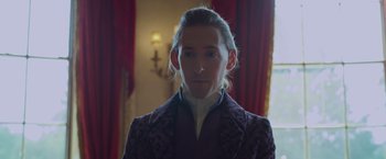 Movie still from “Cinderella” (2021), directed by Kay Cannon – A man with long blonde hair wearing a purple jacket; Close Up shot, Low angle