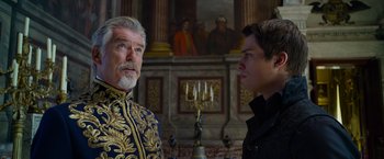 Movie still from “Cinderella” (2021), directed by Kay Cannon – Two men standing next to each other in front of a painting; Close Up shot, Over the shoulder angle