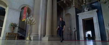 Movie still from “Cinderella” (2021), directed by Kay Cannon – A man walking in front of a building with columns; Wide shot, Low angle