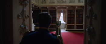 Movie still from “Cinderella” (2021), directed by Kay Cannon – A man and a woman standing in a library; Wide shot, Low angle