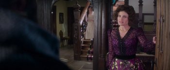 Movie still from “Cinderella” (2021), directed by Kay Cannon – A woman in a purple dress standing in front of a staircase; Medium shot, Over the shoulder angle