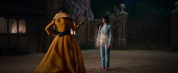 Movie still from “Cinderella” (2021), directed by Kay Cannon – A woman in a blue suit standing next to a man in a yellow suit; Wide shot, Over the shoulder angle