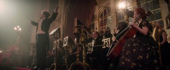 Movie still from “Cinderella” (2021), directed by Kay Cannon – A group of people sitting in a room with musical instruments; Wide shot, Low angle