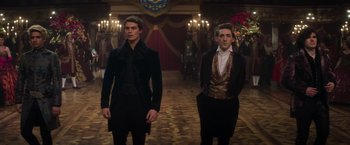 Movie still from “Cinderella” (2021), directed by Kay Cannon – Two men standing next to each other in front of chandeliers; Medium shot, Low angle