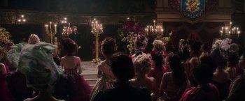 Movie still from “Cinderella” (2021), directed by Kay Cannon – A group of people sitting in front of a stage; Wide shot, Over the shoulder angle