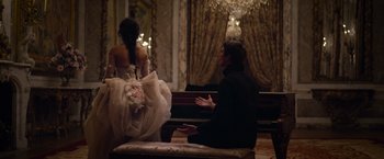 Movie still from “Cinderella” (2021), directed by Kay Cannon – A man and a woman sitting in front of a grand piano; Medium shot, Over the shoulder angle