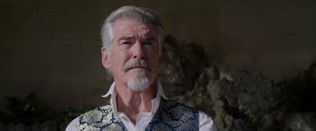 Movie still from “Cinderella” (2021), directed by Kay Cannon – An older man with a white beard wearing a blue vest; Close Up shot, Low angle