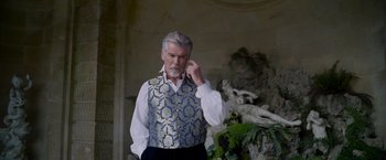 Movie still from “Cinderella” (2021), directed by Kay Cannon – An older man wearing a blue and gold vest; Medium shot, Low angle