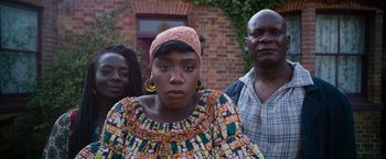 Movie still from “Cinderella” (2021), directed by Kay Cannon – A woman wearing a head scarf standing next to two men; Medium shot, Over the shoulder angle