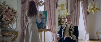 Movie still from “Cinderella” (2021), directed by Kay Cannon – A woman in a white dress standing next to a man in a suit; Medium shot, Over the shoulder angle