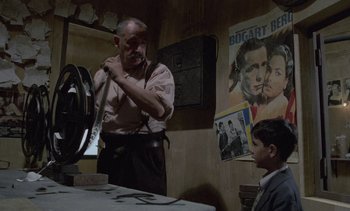 Movie still from “Cinema Paradiso” (1988), directed by Giuseppe Tornatore – An old man and a young boy in a room; Medium shot, Over the shoulder angle