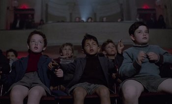 Movie still from “Cinema Paradiso” (1988), directed by Giuseppe Tornatore – A group of young boys sitting in a row of chairs; Medium shot, Low angle
