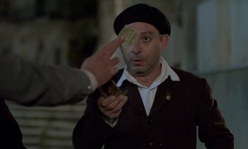 Movie still from “Cinema Paradiso” (1988), directed by Giuseppe Tornatore – A man in a black hat is holding money; Medium shot, Over the shoulder angle