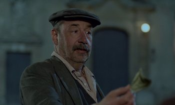 Movie still from “Cinema Paradiso” (1988), directed by Giuseppe Tornatore – An older man wearing a hat and holding a piece of paper; Close Up shot, Low angle