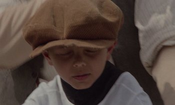 Movie still from “Cinema Paradiso” (1988), directed by Giuseppe Tornatore – A young boy wearing a brown hat and a white shirt; Close Up shot, Low angle
