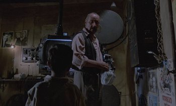 Movie still from “Cinema Paradiso” (1988), directed by Giuseppe Tornatore – A man standing next to another man in a room; Medium shot, Over the shoulder angle