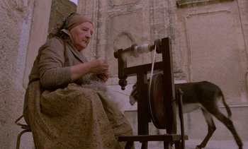Movie still from “Cinema Paradiso” (1988), directed by Giuseppe Tornatore – An old woman is spinning wool on a spinning wheel; Medium shot, Low angle