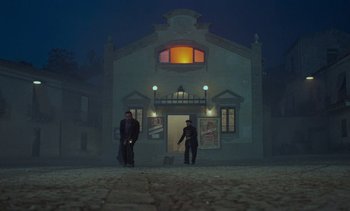 Movie still from “Cinema Paradiso” (1988), directed by Giuseppe Tornatore – Two men standing in front of a building at night; Extreme Wide shot, Low angle