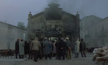 Movie still from “Cinema Paradiso” (1988), directed by Giuseppe Tornatore – A group of people standing outside of a building with smoke coming out of it; Extreme Wide shot, Low angle