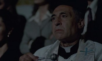 Movie still from “Cinema Paradiso” (1988), directed by Giuseppe Tornatore – A man in a priest's outfit holding a spoon; Close Up shot, Over the shoulder angle