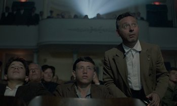 Movie still from “Cinema Paradiso” (1988), directed by Giuseppe Tornatore – Two men are watching a movie in a theater; Medium shot, Low angle