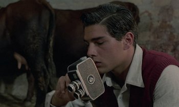 Movie still from “Cinema Paradiso” (1988), directed by Giuseppe Tornatore – A man holding an old fashioned camera up to his face; Close Up shot, Over the shoulder angle