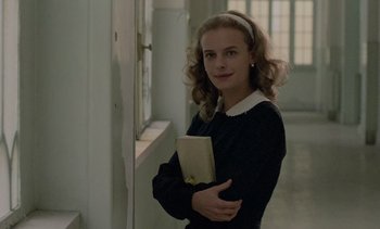 Movie still from “Cinema Paradiso” (1988), directed by Giuseppe Tornatore – A young woman holding a book in a hallway; Medium shot, Low angle