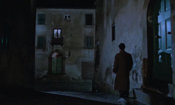 Movie still from “Cinema Paradiso” (1988), directed by Giuseppe Tornatore – A man standing in front of an old building at night; Extreme Wide shot, Low angle