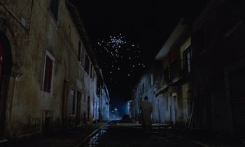 Movie still from “Cinema Paradiso” (1988), directed by Giuseppe Tornatore – A man standing on a street at night with fireworks in the background; Extreme Wide shot, Low angle