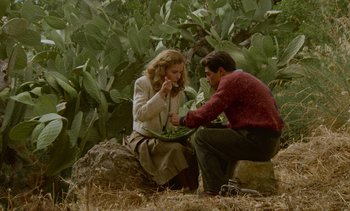 Movie still from “Cinema Paradiso” (1988), directed by Giuseppe Tornatore – A man and a woman sitting on top of a tree stump; Wide shot, High angle