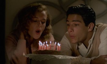 Movie still from “Cinema Paradiso” (1988), directed by Giuseppe Tornatore – A man and a woman blowing out candles on a cake; Close Up shot, High angle
