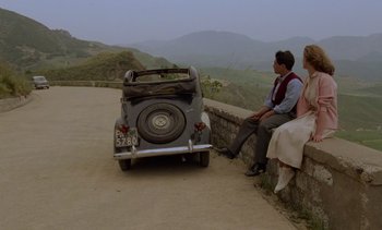 Movie still from “Cinema Paradiso” (1988), directed by Giuseppe Tornatore – A man and a woman sitting next to an old car; Wide shot, High angle