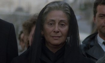 Movie still from “Cinema Paradiso” (1988), directed by Giuseppe Tornatore – An older woman wearing a black veil looking at the camera; Close Up shot, Over the shoulder angle