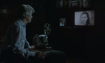 Movie still from “Cinema Paradiso” (1988), directed by Giuseppe Tornatore – A man sitting in front of a tv with an old movie projector; Medium shot, High angle