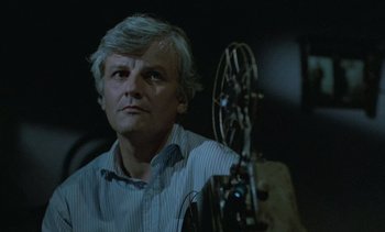 Movie still from “Cinema Paradiso” (1988), directed by Giuseppe Tornatore – An older man is sitting in front of an old movie projector; Close Up shot, Low angle