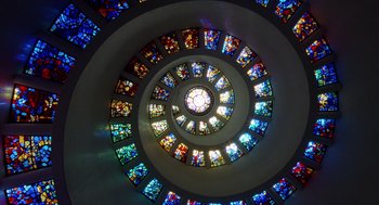 Movie still from “The Tree of Life” (2011), directed by Terrence Malick – A spiral of stained - glass windows inside a building; Extreme Wide shot, Low angle