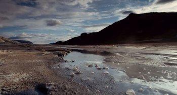 Movie still from “The Tree of Life” (2011), directed by Terrence Malick – A body of water near a mountain under a cloudy sky; Extreme Wide shot, High angle