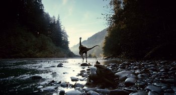 Movie still from “The Tree of Life” (2011), directed by Terrence Malick – A dinosaur walking across a river in a wooded area; Extreme Wide shot, Low angle