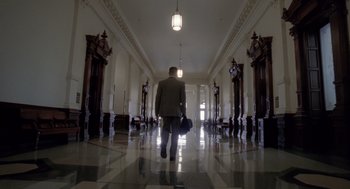 Movie still from “The Tree of Life” (2011), directed by Terrence Malick – A man walking down a hall way holding a suitcase; Extreme Wide shot, Low angle